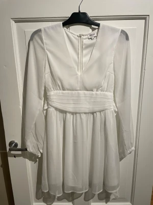 Bubbleroom vit kortklänning med v-ringning - Säljer en vit kortklänning från Bubbleroom med v-ringning och knyte i ryggen. Perfekt till konfirmation och student! Bild 4-5 är när klänningen är knuten i ryggen🌟🌸