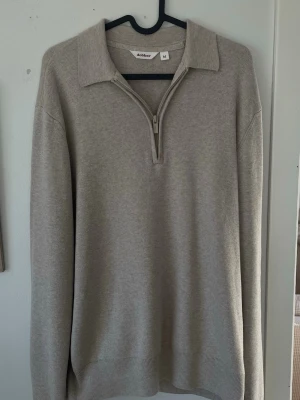 Beige halvzip-tröja från Dobber - Snygg beige stickad tröja från Dobber med halvzip och bred krage. Tröjan har långa ärmar och ribbade muddar vid ärmslut och nederkant. Perfekt för lager på lager och enkel att matcha med olika outfits. Nypris: runt 700-800kr