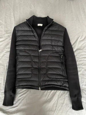 Svart Moncler Cardigan - Tjena! Jag säljer min asfeta Moncler cardigan i storlek M. Den är perfekt för nästan alla väder, man kan tro att eftersom den är så tunn så blir man kall fast den håller värme extremt bra. Den är väldigt skön och passar till allt. Har NFC scan och några lappar samt ”Moncler triangeln”. Det är bara att skriva ifall ni har några funderingar 🤩 