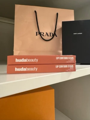 Huda Beauty Lip Contour Stain 2-Pack - Säljer två Huda Beauty Lip Contour Stain i snyggt nude-färgat hylsa. Pennorna är lätta, infuserade med arganolja och ger långvarig färg till läpparna. Perfekt för att skapa definierade och fylliga läppkonturer. 2 stycken för 179