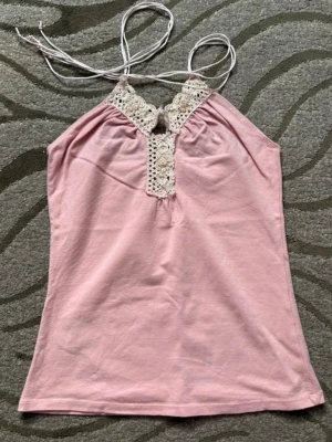 rosa halterneck topp med spets - supersöt rosa halterneck topp som man knyter med spetsdetaljer. storlek S, hör av er vid frågor!! 