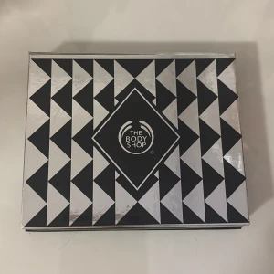 The Body Shop ögonskuggspalett - Snygg ögonskuggspalett från The Body Shop med fyra nyanser: koppar, mörkblå, mörkgrå och silver. Paletten har en spegel i locket och kommer i en stilren svart och silver ask med grafiskt mönster. Perfekt för att skapa både dramatiska och neutrala looks.