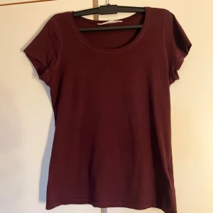 Mörkröd basic t-shirt i bomull - Enkel och stilren mörkröd t-shirt med rund halsringning och korta ärmar. Modellen är rak och passar perfekt till jeans eller kjol. Tillverkad i mjuk bomull som känns skön mot huden.