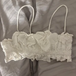 Vit omlott linnetopp med snörning XS - Supersöt vit linnetopp från hm i storlek XS. Toppen har tunna axelband, omlott-design med snörning i ryggen och volangdetaljer som ger en romantisk vibe. Materialet är mjukt linne och toppen är ärmlös, perfekt för varma dagar.