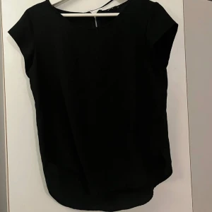 Svarta blusar med rund och v-ringad hals - Två svarta blusar från Indiska i mjukt material. Ena har rund hals och den andra har v-ringad hals. Båda har korta ärmar och en rak, något längre passform baktill. Perfekt för dig som gillar stilrena och enkla toppar.