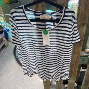 Randig t-shirt från Holly & White - Snygg t-shirt från Holly & White i vitt och marinblått med klassiskt randigt mönster. T-shirten har rund halsringning och korta ärmar. Tillverkad i mjuk bomull, perfekt för en avslappnad och stilren look.