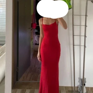 Röd långklänning med öppen rygg - Snygg röd långklänning med smala axelband som går att justera, figurnära passform. Och extra tyg vid brösten vilket syns på bilden. Klänningen har en öppen rygg och raka linjer framtill. Väldigt stretchig så passar S-L. Den är lite satin / baddräkt material. Jag är 169 cm lång och den går ner till vaderna på mig💕