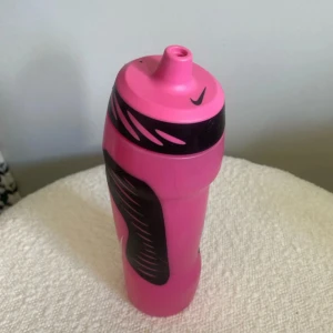 Nike Sport Water Bottle 24oz Pink - Snygg och praktisk sportflaska från Nike i rosa och svart, rymmer 24oz/0,7L. Tillverkad i BPA-fri plast, ergonomisk design och enkel att använda. Flaskan är i gott skick med mindre yttre slitage, perfekt för träning eller vardagsbruk.