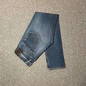 Replay Anbass hyperflex jeans i storlek W32/L32 - Replay Anbass hyperflex jeans i storlek W32/L32. Mörkblå denim med slim fit-passform och stretch som gör dem bekväma. Bra skick utan hål eller fläckar, bara lite små slitningar. Nypris runt 1500–2000 kr.  Mått: A (midja): 42 cm B (lårvidd): 28 cm C (fotvidd): 16 cm D (innerbenslängd): 80 cm  Säljes för 499 kr. 