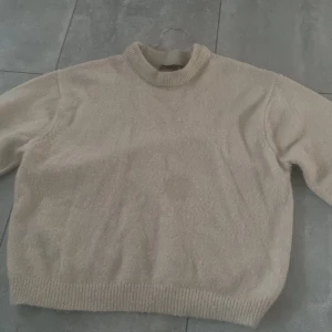 Beige stickad tröja från 157, S - Mysig beige stickad tröja från 157 i storlek S. Tröjan har en enkel design med ribbad hals, ärmslut och nederkant. Perfekt för dig som gillar neutrala färger och vill ha en klassisk look. Långärmad och med normal passform. Säljs inte längre!!!