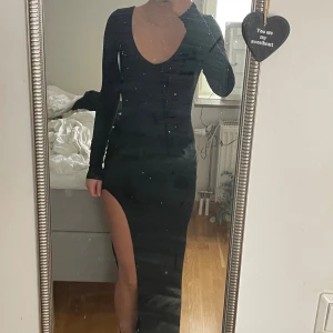 Svart långklänning med slits - Säljer denna svarta långklänning med ett superskönt material, den har en fin slits på sidan och sitter perfekt på kroppen. Klänningen formar kroppen och har ett strechigt material