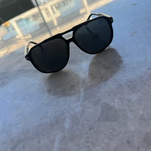  Tom Ford Raoul  - Snygga svarta pilotglasögon från Tom Ford med klassisk aviator-form och mörka linser. Bågarna har diskreta gulddetaljer och är tillverkade i Italien. Perfekt för dig som vill ha en stilren och exklusiv look.