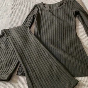 Ribbade svarta byxor från SHEIN - Säljer ett par svarta ribbade byxor från SHEIN i storlek S. Byxorna har en bred, rak passform och är tillverkade i ett stretchigt material med 5% elastan. Perfekta för en chill och trendig look.