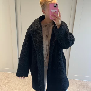 Svart teddyjacka i oversized modell - Mysig svart teddyjacka från H&M i oversized passform. Jackan har stora slag, lång ärm och är tillverkad i fluffigt teddy-material. Perfekt för kalla dagar när du vill vara både varm och snygg.