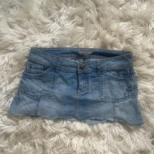 Ljusblå jeanskjol från Esprit - Säljer en snygg ljusblå jeanskjol från Esprit med klassiska fickor fram och bak, bälteshällor och knappstängning. Kjolen har en kort modell och är gjord i mjukt denimtyg. Perfekt för dig som gillar en avslappnad och trendig stil.