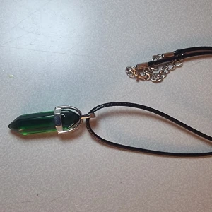 Halsband med grön kristallhänge - Hänge med halsband i läder liknande material samt liten kedjedel. Smyckes storlek: ca 41mm x 13mm  Kedjestorlek: ca 45cm - 50cm Observera att ditt smycke kan skilja sig något från bilderna på grund av naturliga material.🎈Fri frakt❤️