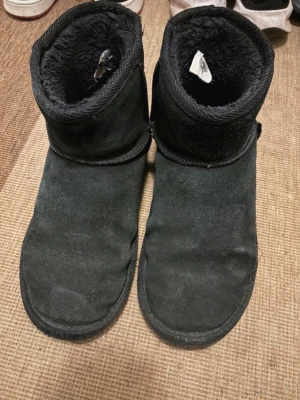 Svarta uggs - Mina gamla uggs som jag köpte från even&odd i zalando. Dom har hål som visas på bilden. Hålet gör att dom inte är vattentäta, men man kan ha dom i snö och jag sprayade dom nyligen.