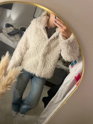 Vit teddyjacka med krage - Säljer en fluffig och supermjuk vit teddyjacka med stor krage. Jackan har en oversized passform och är gjord i ett lurvigt material som ger en riktigt cozy vibe. Perfekt för kyliga dagar när du vill vara både varm och stylish. Jackan är helt slutsåld