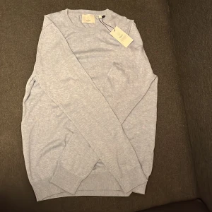 Ljusblå stickad tröja  - Jag säljer denna ljusblåa stickade tröjan från bläck/MQ, den är oanvänd och har lappar kvar. Den är i storlek S (herr)