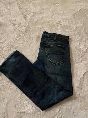 Mörkblå Lee jeans straight fit - Säljer ett par mörkblå jeans från Lee med klassisk femficksdesign och färgning framtill. Jeansen har rak passform och normal midja, perfekt för dig som gillar en tidlös look. Materialet är robust denim i bomull.