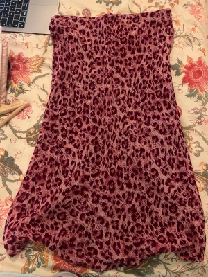 Leopardmönstrad kjol från Hennes - Säljer en snygg långkjol från Hennes i leopardmönster med mörklila och rosa toner. Kjolen har en rak passform och är tillverkad i ett mjukt, lätt material som faller fint. Perfekt för dig som vill sticka ut med ett djurmönster.