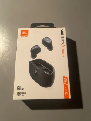 JBL Vibe Buds - JBL Vibe Buds är trådlösa hörlurar med djup bas, smart ambient-läge och handsfree-samtal. Upp till 32 timmars batteritid, IP54 vatten- och dammtålighet, Bluetooth 5.2, touchkontroller och JBL Equalizer. Produkten är ny i förpackning utan synligt slitage.