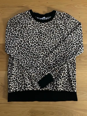 Leopardmönstrade mjukis set - Säljer ett par mjukisbyxor med leopardmönster i svart, beige och vitt. Byxorna har resår i midjan och är gjorda i ett mjukt och bekvämt material, perfekta för chill dagar hemma. De har en rak passform och elastiska muddar upptill.