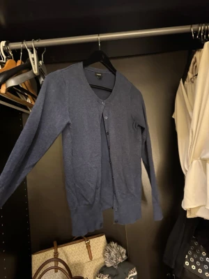 Mörkblå kofta från Lindex - En stilren mörkblå kofta från Lindex i storlek S. Koftan har rund halsringning, långa ärmar och knäppning framtill med matchande knappar. Perfekt att slänga över en t-shirt eller linne för en chill look.