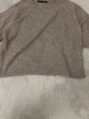 Beige stickad tröja från 157 - Mysig beige stickad tröja från 157 i storlek S. Tröjan har rund hals och ribbade muddar vid ärmslut och nederkant. Perfekt för lager-på-lager och chill dagar. Enkel design som är lätt att matcha med jeans eller mjukis.