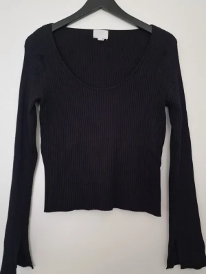 H&M svart stickad trõja XL - Säljer en svart ribbad topp från H&M i storlek XL. Toppen har lång ärm, rundad djup halsringning och är croppad i modellen. Materialet är mjukt och stretchigt, perfekt för att styla med jeans eller kjol. Enkel och stilren design som funkar året runt. Passar även för L. Fint skick
