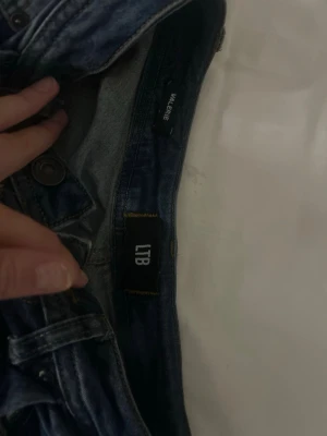 Mörkblå bootcut jeans från LTB - Snygga mörkblå jeans från LTB med klassisk femficksdesign och lätt slitna detaljer. Modellen har bootcut-ben vilket e perfekt för dig som har Stockholmsstil. Längden är 32 och storleken 24. Kan diskutera pris!