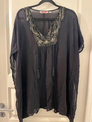 Svart flammig tröja från Indiska med guldiga paljetter  - En svart flammig tröja med olika sorts paljetter 