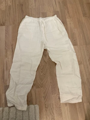 Vita linnebyxor från mango - Säljer ett par vita linnebyxor från Mango i storlek S. Byxorna har avslappnad passform, elastisk midja med snörning och fickor både fram och bak. Perfekta för varma dagar och chill stunder. Materialet är linne som ger en skön och luftig känsla. 