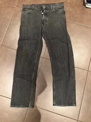 Svarta raka jeans från Weekday - Säljer ett par svarta jeans från Weekday med rak passform och klassisk femficksdesign. Jeansen har knappgylf och är tillverkade i kraftig bomullsdenim. Perfekta för dig som gillar en enkel och clean look.