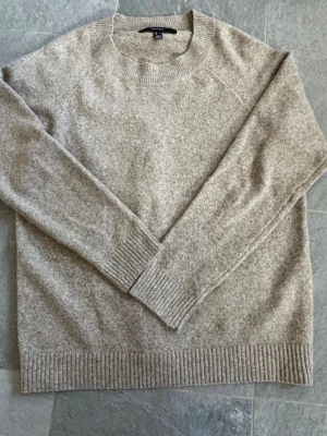 Beige stickad tröja från Vero Moda - Supermjuk beige stickad tröja från Vero Moda med rund halsringning och ribbade muddar. Perfekt för lager-på-lager och chill dagar. Enkel och stilren design som är lätt att matcha med jeans eller kjol.