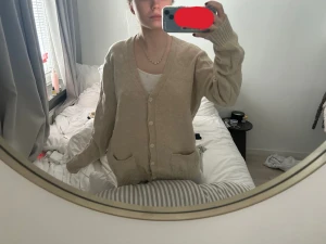 Beige oversized kofta med knappar - Mysig beige kofta med v-ringning och stora knappar framtill från brandy Melville. Koftan har två fickor och långa ärmar med breda muddar. Oversized passform
