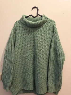 Grön stickad polotröja oversized - Stickad tröja i mjuk grön nyans med hög krage. Använd endast 2 gånger och i mycket fint skick, inga synliga slitningar eller noppor. Storlek XS/S men har en oversize/passform som även passar M beroende på hur man vill att den ska sitta. Skön och varm – perfekt till höst och vinter. Säljs då den tyvärr inte kommer till användning.