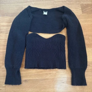 Svart ribbad bolerotopp från SHEIN - Säljer en svart ribbad bolerotopp från SHEIN i storlek XS. Setet består av en croppad, ärmlös topp med sweetheart-ringning och en matchande bolero med långa ärmar. Materialet är mjuk och stretchig polyester, perfekt för att skapa en cool och trendig look.