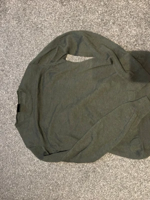 Mörkgrön stickad tröja Oscar Jacobson - Snygg mörkgrön stickad tröja från Oscar Jacobson i storlek M. Tröjan har rund halsringning, långa ärmar och ribbade muddar vid ärmslut och nederkant. Perfekt för lager på lager under höst och vinter. Tröjan har ett litet hål på baksidan av armen syns ytterst lite men utöver det är tröjan i perfekt skick 🙂