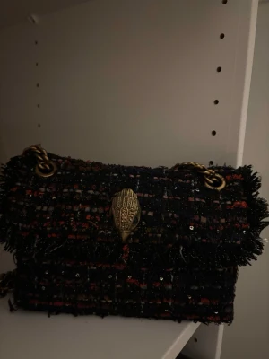 Kurt Geiger Kensington axelväska - Säljer en Kurt Geiger Kensington axelväska med grov kedja i antikguld och snyggt rutigt tyg i mörka toner.  Perfekt storlek för det viktigaste. 