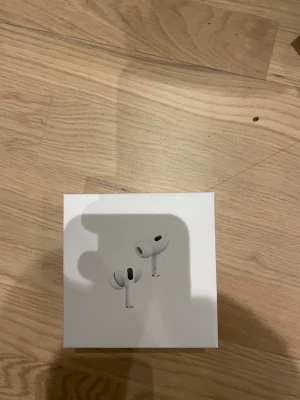 AirPods Pro 2nd Generation with MagSafe Charging Case - Säljer ett par Apple AirPods Pro 2nd Generation med MagSafe-laddningsetui. Komplett i originalförpackning med laddkabel och tillbehör. Produkten ser ut att vara i mycket gott skick, perfekt för dig som vill ha trådlösa hörlurar med aktiv brusreducering och hög ljudkvalitet.