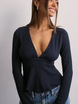 Marinblå topp med v-ringning - Snygg marinblå topp med djup v-ringning och långa ärmar. Toppen har en knytning som man kan ha i midjan men även i ryggen. Har använt fåtal gånger och känns som ny!