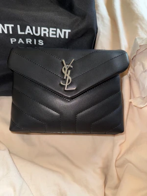 Ysl Loulou bag - Väska från ysl, svart!  Endast använd ett fåtal gånger.  En liten tråd som släppt inuti väskan (inget märkvärdigt) Och ett litet intryck på ena sidan (se sista bild) Säljs för att jag inte får användning för den. 😕  Har box, dustbag och kort. Inget kvitto 🩷 Pris går att diskutera 
