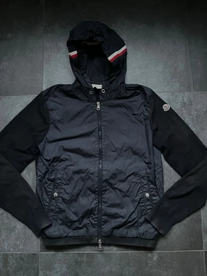 Moncler cardigan - Tjena, säljer nu denna riktigt snygga och populära Moncler cardiganen, den är i använt skick, solblekt på vissa ställen, saknar snörena, finns ett pinehole och att den är aningen smutsig, hör av er vid frågor och funderingar🙌🤝