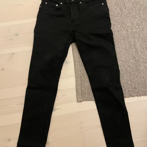 Slim Jeans | DRESSMANN - Svarta jeans från Dressmann i storlek 28-30. Modellen är slim med smal passform och klassisk femficksdesign. Materialet är mjukt och stretchigt, vilket gör dem riktigt bekväma. Perfekt för dig som gillar en stilren och enkel look.