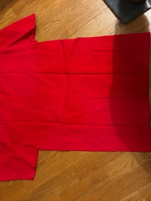 Röd t-shirt från B&C Collection - Säljer en röd t-shirt från B&C Collection med vit tryck på framsidan som visar texten 'Born to ski wild' och 'St. Anton Arlberg' samt en grafisk design med skidtema. T-shirten har korta ärmar och är gjord i mjuk bomull. Perfekt för dig som gillar skidåkning och vill sticka ut.