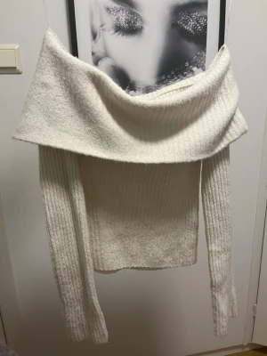 Offshoulder ribbad tröja från H&M - Säljer en krämvit ribbstickad offshoulder-tröja från H&M i storlek XS. Tröjan har långa ärmar och en bred, nedvikt krage som ger en snygg offshoulder-look. Perfekt för dig som vill ha en stilren och mysig vibe.