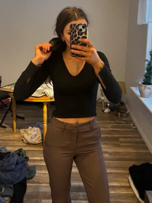 Bruna kostymbyxor med hög midja - Säljer ett par stilrena bruna kostymbyxor med hög midja med botcut.  Materialet känns mjukt och följsamt.