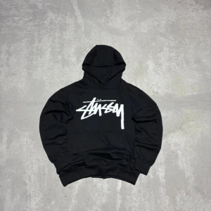 Stussy hoodie - Säljer denna snygga Stussy tröjan. ✅ Mycket gott skick, inga skador. ✅ Trycket är intakt och sprickfritt. ✅ Snyggt snitt. Etiketten säger storlek L, men den passar mer som en 160cm skulle jag säga. Använd gärna måtten nere!  Mått: Längd: 59 cm Bredd: 49 cm Ärmlängd från hals: 64 cm. Kan gå ner i pris vid snabb affär!