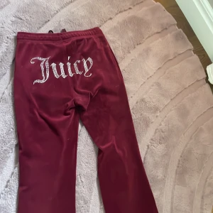 Vinröda juicy byxor  - Säljer mina vinröda juicy byxor pga förstora. De är uppsydda och benen är nu 67cm från grenen. Passar perfekt på mig i längden och jag är 150. Diamanterna där bak sitter fast och ramlar inte av. Hör av dig om frågor osv!💗